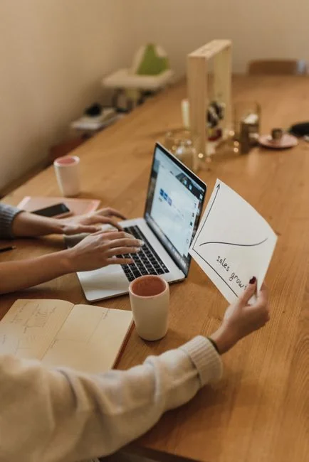 gallery-6 Person using smartphone for stock market analysis at home office.
